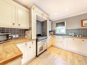 a kitchen with white cabinets and wooden floors at Cloister Cottage - Uk3463 in Ellingham