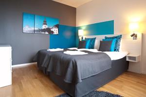 a bedroom with a large bed with blue walls at Sky Hotel Apartments Tornet in Linköping +13 photos