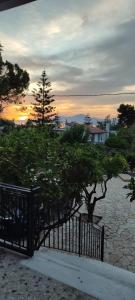 a fence with a tree in front of a sunset at aggelos home in Kato Alepochori +12 photos