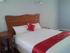 1 dormitorio con 1 cama grande con almohadas rojas y blancas en Tumaini Gardens, en Kajiado