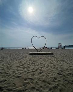 a heart sculpture on a beach with the sun behind it at Daniels apartment in Shëngjin +2 photos