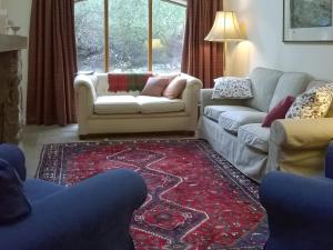 a living room with two couches and a red rug at Gushat Cottage in Strathtay