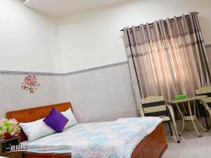 a small bedroom with a bed and a curtain at Nhà nghỉ 72 in Long Hai