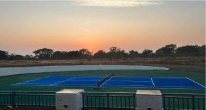 a tennis court with the sunset in the background at Royal Goldfieldd Club Resort Ltd in Dapoli +3 photos