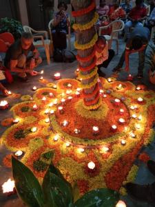 a group of people sitting around a tree with lit candles at Hotel Alka in Varanasi