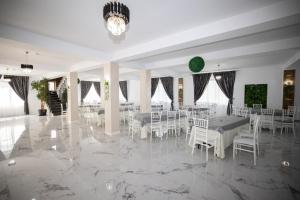 a banquet hall with white tables and white chairs at Rem Garden in Novaci