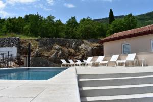 een zwembad met ligstoelen naast een huis bij Brseč Villa AnDa s apartmanima i bazenom in Brseč