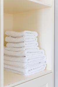 een stapel witte handdoeken op een plank bij Villa Porto Rondo in Agios Prokopios