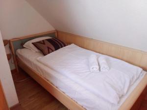 a small bed with white sheets and slippers on it at Dworek Łeba in Łeba
