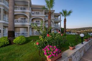 a large apartment building with palm trees and flowers at Arkadia Hotel in Kypseli