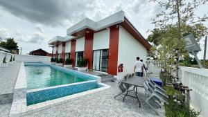 a man standing in front of a house with a swimming pool at ดาด้าพูลวิลล่า in Ban Pa Ngiu