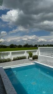 a swimming pool in front of a white fence at ดาด้าพูลวิลล่า in Ban Pa Ngiu
