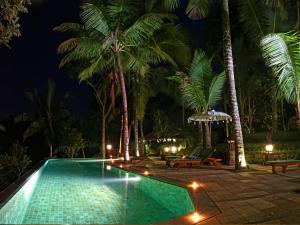 a swimming pool with palm trees at night at Toya Retreat Villa in Tegalalang