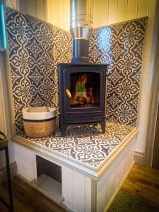 a fireplace sitting on a bench in a room at Unique Retreat Shepherd's Hut in Robeston Wathen +8 photos
