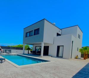 a white villa with a swimming pool in front of it at Vila OASIS - Zadar, Vrsi in Vrsi