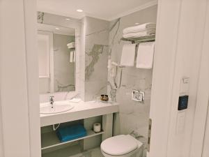 a white bathroom with a sink and a toilet at Ibiscus Hotel in Rhodes Town