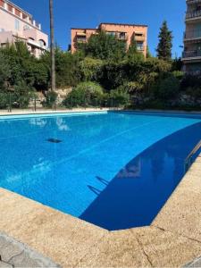 una grande piscina blu con edifici sullo sfondo di Havre cosy et familial, garage, centre ville, dans la cité des Potiers a Vallauris