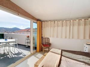 una camera da letto con un letto e un balcone con un tavolo di Havre cosy et familial, garage, centre ville, dans la cité des Potiers a Vallauris