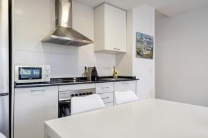 Una cocina con gabinetes blancos y un horno de estufa. en Hauzify I Apartament Diana, en Sant Feliu de Guíxols