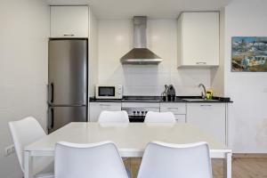 cocina con mesa blanca y sillas blancas en Hauzify I Apartament Diana, en Sant Feliu de Guíxols