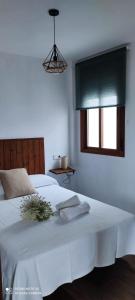 a bedroom with a white bed with a window at Apartamentos Bolonia - M a n u e l a in Bolonia