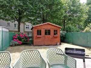 a small wooden shed sitting in a yard with chairs at Antwerp horizon in Borsbeek