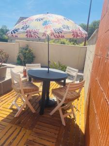 a table and two chairs and an umbrella on a patio at Appartement indépendant chez l'habitant in Rosny-sur-Seine