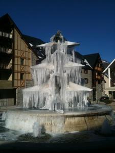 une fontaine recouverte de glace devant un bâtiment dans l'établissement Au Chant Des Marmites, à Saint-Lary-Soulan