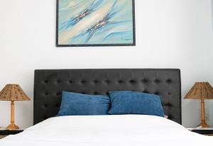 a bed with blue pillows and a painting above it at Utopia in Palm Beach in Port Edward +145 photos