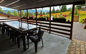 eine Terrasse mit einem Holztisch und Stühlen und Blumen in der Unterkunft Vatra Muntilor in Neagra Şarului