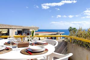 a table with plates and glasses on a balcony with the ocean at Villa Angelina - Mare Privato in Cannizzaro