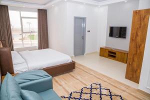 a bedroom with a bed and a tv and a couch at itten plaza blue in Salalah