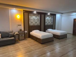 two beds in a room with a couch and a couch at itten plaza blue in Salalah