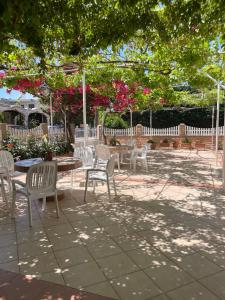 a patio with white chairs and tables and pink flowers at Buganvillas Studios in Preveza