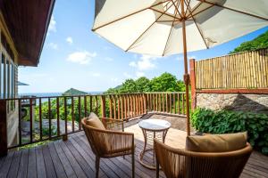 a deck with a table and chairs and an umbrella at Dusit Buncha Koh Tao by Riya Group in Ko Tao