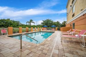 a swimming pool with patio furniture and a building at Comfort Inn Fort Myers Northeast in Fort Myers