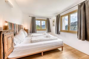 a bedroom with a bed with white sheets and windows at Haus Haemmerle mit Ski in - Ski out in Damuls