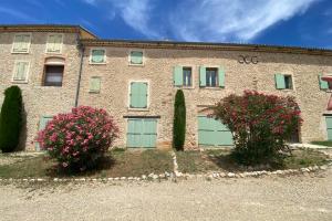 a brick building with green garage doors and pink flowers at 04B2 Beautiful studio in a mas provençal - pool in Brunet