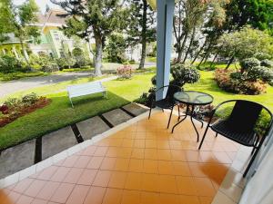 eine Veranda mit einer Bank und einem Tisch und Stühlen in der Unterkunft Vila kota bunga in Cikundul