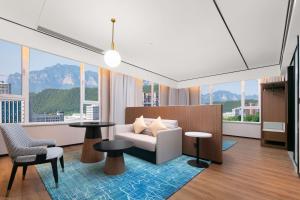 a living room with a couch and tables and windows at Hilton Garden Inn Handan She County in Handan