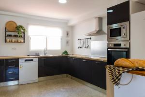 a kitchen with black cabinets and white appliances at Apartamento en el Paseo de Oliva in Oliva +12 photos