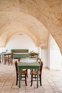a dining room with green tables and wooden chairs at Masseria Gorgognolo in Ostuni