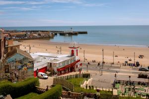 Una vista de una playa con un edificio y un faro. en Lighthouse View - Amazing sea and beach view - Free Sky TV including Sports and Movies - Fast WIFI - Free Private Parking, en Scarborough