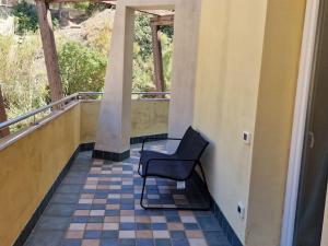 una sedia nera appoggiata su un balcone con pavimento piastrellato di Corallo Bilocale Vista Collina a Nebida