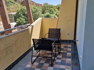 two chairs and a table on a balcony at Corallo Bilocale Vista Collina in Nebida