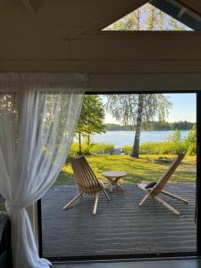 OgureckajaLangino Land的两把椅子和一张桌子,位于带窗户的甲板上