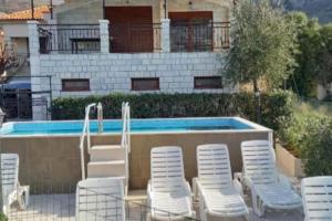 a group of white chairs and a swimming pool at Apartment Marija in Risan
