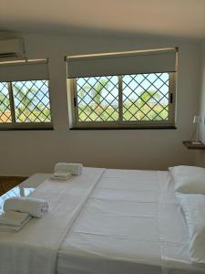 Un dormitorio con una gran cama blanca con dos ventanas. en Cerasella house, en Castellammare di Stabia