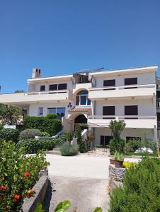 a large white building with some plants and flowers at Rooms Helena in Krk