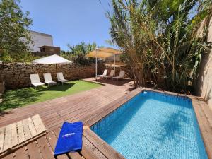a swimming pool with a deck and chairs and an umbrella at Casa Can Bernat in Santanyi